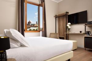 una camera d'albergo con un letto bianco e una finestra di Essence Hotel a Firenze