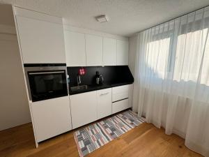 a white kitchen with a sink and a microwave at Apartment Oberrüti in Oberrüti