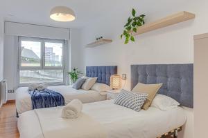 ein Schlafzimmer mit zwei Betten und einem Fenster in der Unterkunft Blue Ocean Apartment in A Coruña