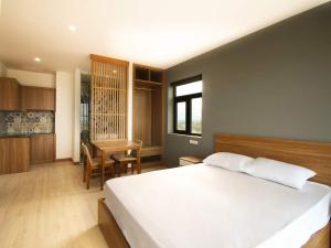 a bedroom with a large white bed and a desk at LaLa Apartment and Hotel in Danang