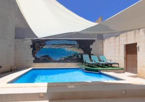 una piscina con due sedie blu e un grande edificio di Hollies a Qala
