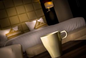 a white coffee cup sitting on top of a white bed at Golden Ocean Hotel in Doha