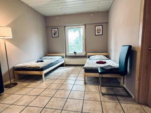 a room with two beds and a chair and a window at Apartment OchtrUP II Outlet & Zentral in Ochtrup