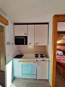 eine kleine Küche mit Herd und Mikrowelle in der Unterkunft Condo in val thorens by AlpStays in Val Thorens + 6 Fotos