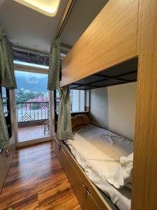 een stapelbed in een kamer met een groot raam bij Joey's By The Ganges in Rishīkesh +190 foto's