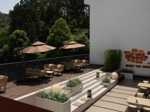 an outdoor patio with tables and chairs and umbrellas at Yanyu Yunxi Resort Hotel 烟雨云兮酒店 in Fenghuang County