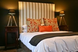 1 dormitorio con 1 cama con almohadas de color naranja y blanco en One Paddock Currency Creek Winery Villas, en Currency Creek