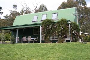 uma casa com um telhado verde e cadeiras no quintal em The Barn at Charlottes Hill em Healesville