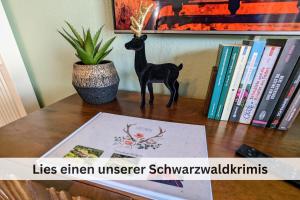 a figurine of a deer on a table next to books at FeWo Hirschperle - Black Forest Stay in Sasbachwalden +16 photos
