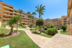 a walkway with palm trees in front of a building at Beautiful 2 Bed Apartment Los Pacos in Las Lagunas Mijas