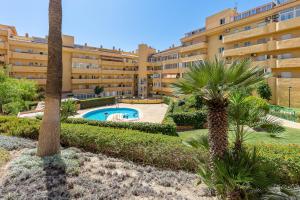 a large apartment building with a swimming pool and palm trees at Beautiful 2 Bed Apartment Los Pacos in Las Lagunas Mijas