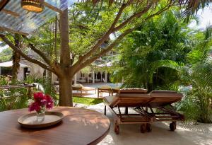 a patio with a table and chairs and a tree at Palm Garden ECO Boutique Hotel No Kids under 12 in Watamu