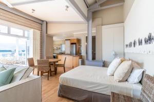 a bedroom with a bed and a dining room at Vibey Modern Apartment in Knysna