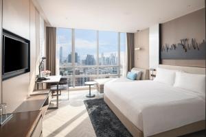 Una habitación de hotel con una cama grande y un escritorio. en Pathumwan Princess Hotel, en Bangkok