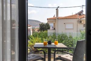 a table with two glasses of orange juice on a balcony at Orion Luxury Apartments in Nafplio