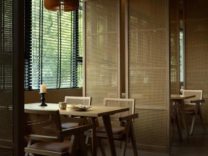 a dining room with tables and chairs and windows at Yanyu Yunxi Resort Hotel 烟雨云兮酒店 in Fenghuang County