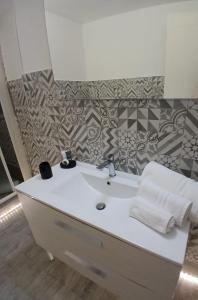 a bathroom with a white sink and a tile wall at Residenza Aura in Olbia +4 photos