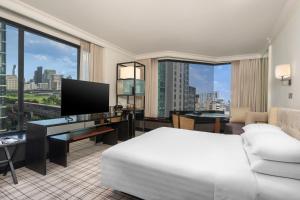 a hotel room with a bed and a desk with a television at Grand Hyatt Erawan Bangkok in Bangkok