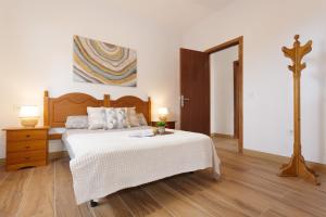 a bedroom with a white bed and a wooden floor at Casa en El Campo in Tacoronte