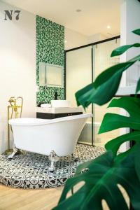 a bathroom with a white tub and a green wall at H'homestay quận 1 - N7 in Ho Chi Minh City