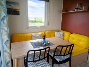 a dining room with a table and a yellow couch at Regenbogen Tossens in Butjadingen