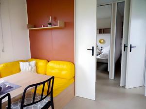 a living room with a yellow couch and a table at Regenbogen Tossens in Butjadingen