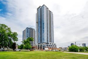 a tall building in a city with a grass field at City View 1BR Condo - King Bed & Private Balcony in Kitchener