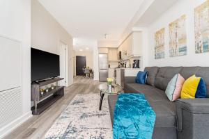 a living room with a gray couch and a flat screen tv at Luxury 1BR King Bed Unit - Private Balcony in Kitchener