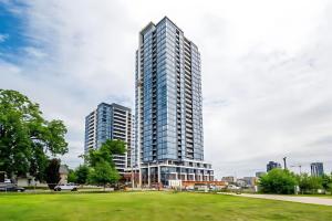a tall building in a city with a park at Luxury 1BR King Bed Unit - Private Balcony in Kitchener