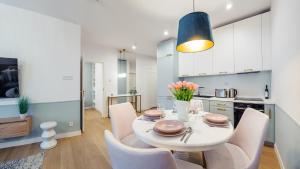 a kitchen and dining room with a white table and chairs at Apartamenty Tukan- Polanki Aqua - Holiday City in Kołobrzeg +133 photos