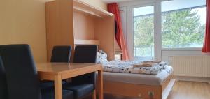 a room with a desk and a bed with a window at Herzerl Apartment in Sankt Englmar
