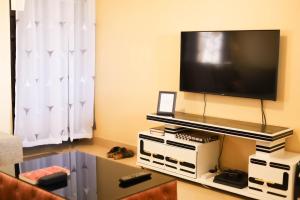a living room with a flat screen tv on a wall at Bethh serviced Apartments in Ruiru