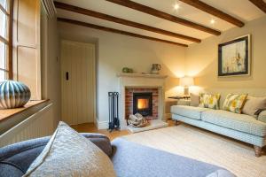 ein Wohnzimmer mit Couch und Kamin in der Unterkunft Riverside Cottage Alstonefield Peak District in Alstonfield