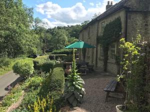 einen Garten mit einem Picknicktisch und einem Sonnenschirm in der Unterkunft Riverside Cottage Alstonefield Peak District in Alstonfield