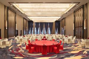 une grande salle de banquet avec des tables et des chaises blanches dans l'établissement Wanda Realm Guangyuan, à Guangyuan