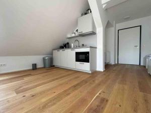 an empty living room with a kitchen and wooden floors at AM1114 - Moderne Monteurwohnung Übergangswohnung in Amberg