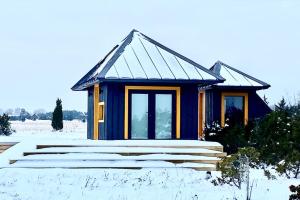 a small blue house with snow on the ground at Japandi Guesthouse in Muhu in Võiküla