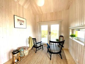 a living room with two chairs and a window at Japandi Guesthouse in Muhu in Võiküla +9 photos