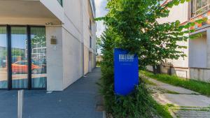 un panneau bleu sur le côté d'un bâtiment à côté d'un arbre dans l'établissement VacationClub - Boulevard Residence Apartament 22, à Ustronie Morskie