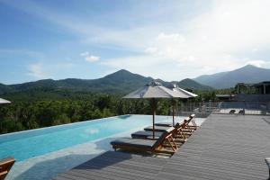 a swimming pool with lounge chairs and an umbrella at Varivana Resort Koh Phangan, The Centara Collection in Thong Sala