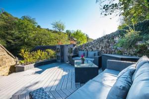 d'une terrasse avec un canapé, des tables et un mur en pierre. dans l'établissement Duck Cottage Milldale Alstonefield Peak District, à Alstonfield