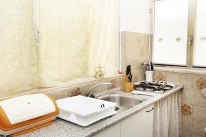 Una pequeña cocina con fregadero y estufa. en OLTREMARE casa per vacanze con terrazzo e 3 camere con 6 PL, en Casarano