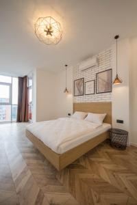 a white bedroom with a large bed and a chandelier at Design Apartments with Panoramic View in Kyiv