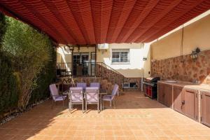 a patio with purple chairs and a table and a kitchen at Refugio de Ensueño Cerca de la Alhambra y Sierra Nevada in Cenes de la Vega
