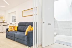 un canapé bleu avec des coussins jaunes dans un salon dans l'établissement Boutique Plaza Catalonia Suites Cornellá, à Cornellà de Llobregat