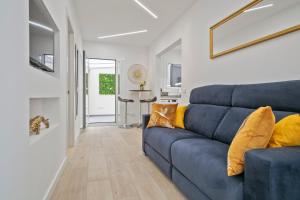 un salon avec un canapé bleu avec des coussins jaunes dans l'établissement Boutique Plaza Catalonia Suites Cornellá, à Cornellà de Llobregat