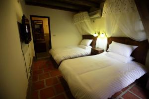2 Betten in einem Hotelzimmer mit weißer Bettwäsche in der Unterkunft Red Tomato B&B in Jinsha