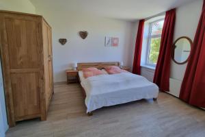 a bedroom with a bed and a window with red curtains at Ferienwohnung Biethahn - Gaarden in Groß Brodersby