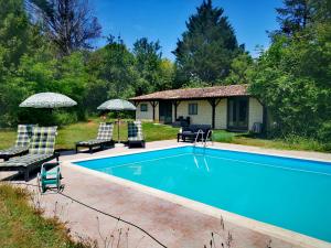 a swimming pool with two chairs and a house at Quatre Saisons Été in Bergerac