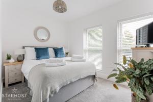 a white bedroom with a bed with blue pillows at StarHost Residences - Brand New 2 bed apartment in Newbury Centre in Newbury